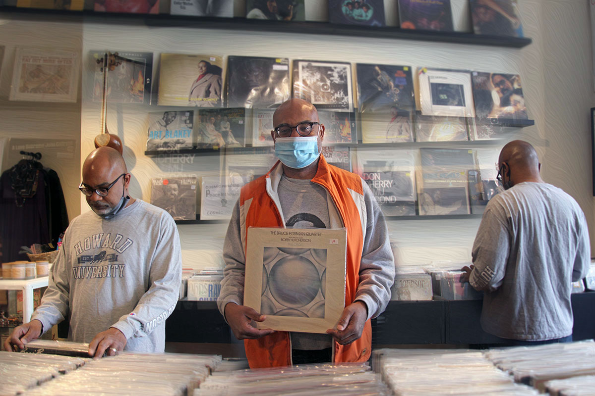 A montage of three photos showing the shelves of a record store and a man, in three separate positions, digging through the stacks. In the center, he holds up an album.