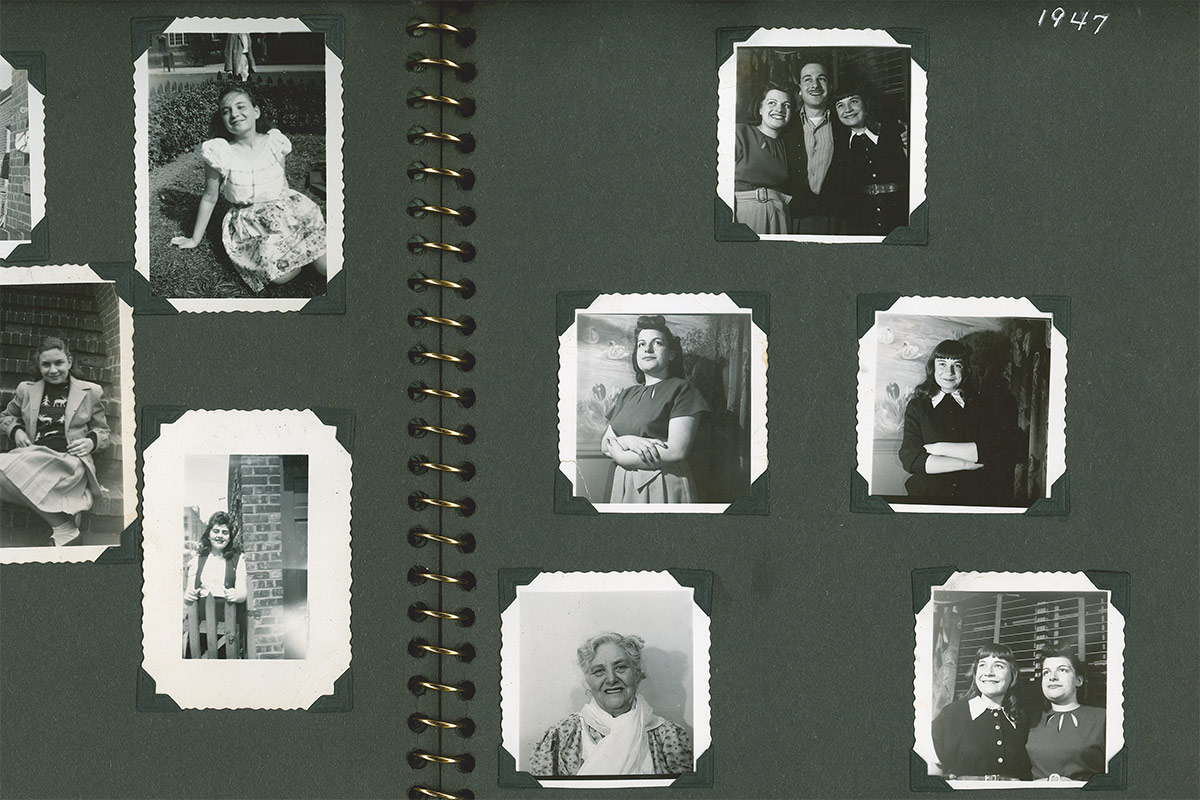 A spread in a photo album with black pages and small black-and-white portraits of people mounted inside.