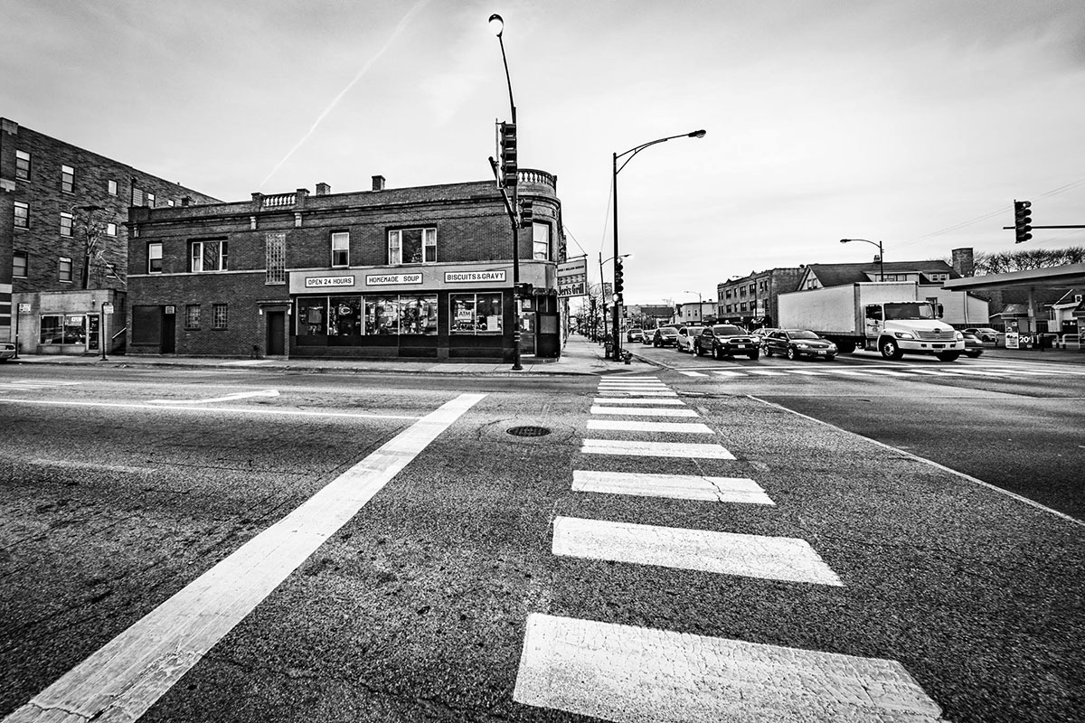 A brick building with large windows seen from across the street. Black-and-white photo.