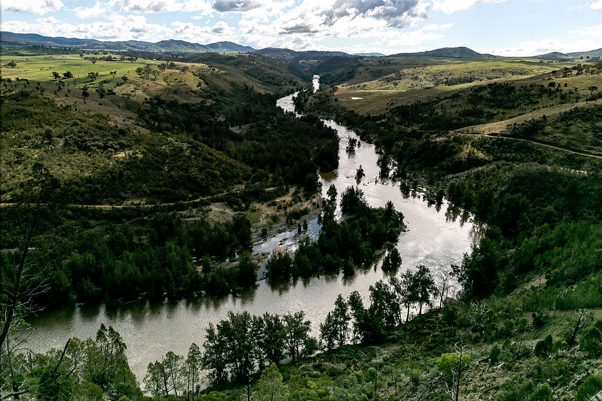 Silvery river curving through green hills.