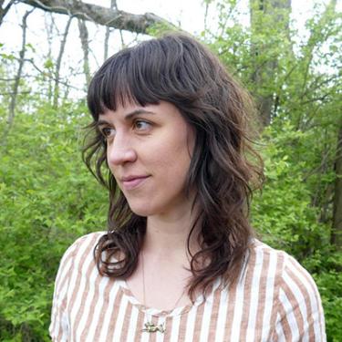 Portrait of a woman with long wavy brown hair outdoors.