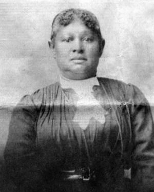 A woman poses with a dark long-sleeve blouse and white collar.  Black-and-white photo.
