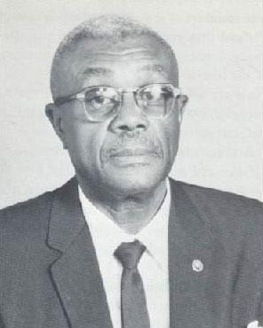 Elder man with glasses, short hair, and dark suit jacket and tie.  Black-and-white photo.