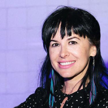 Headshot of Gretchen Davidson with long dark hair and dangling ribbon earrings in turquoise and purple.