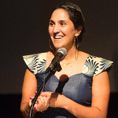 Headshot of Selina Morales speaking into a microphone on stage.