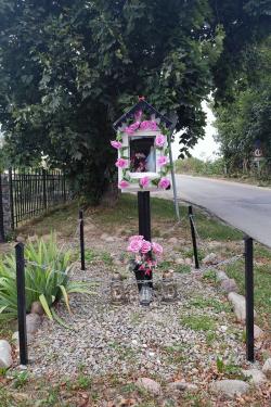 A roadside shrine adorned with pink roses.