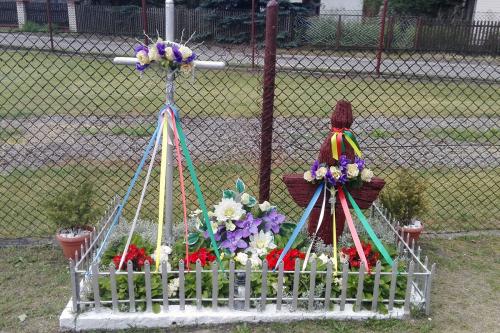 A small roadside shrine decorated with colored ribbons and white, red, and purple flowers.