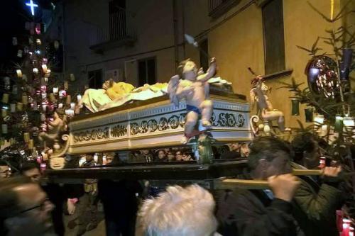 Men carry a statue of Jesus in a coffin in a procession at night.