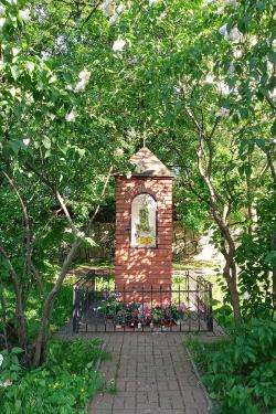 A red brick shrine amid lush greenery, with a brick walkway leading to it.
