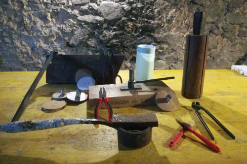 An assortment of handmade wooden tools, plus metal pliers, arranged on a work table. 