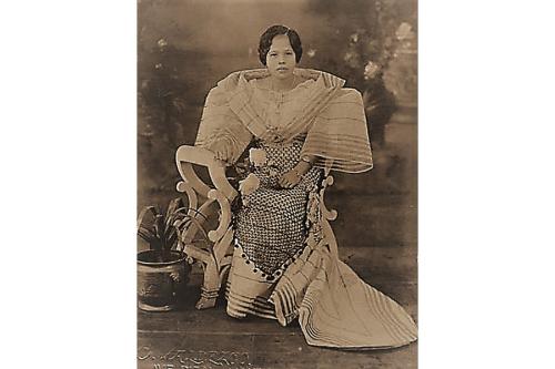 Old black-and-white photograph of a Filipina woman posing in a white dress with extremely wide sleeves, each about the width of her torso.
