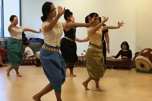 Women dancers rehease in sync, with arms and fingers outstretched.