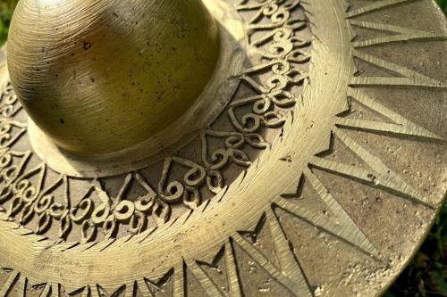 Closeup of a bronze gong with concentric, geometric patterns carved into its surface.
