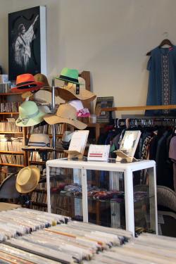 A display in the store with a hat rack, clothing racks, and a display of books.