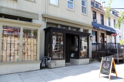 The exterior of a record shop in a row of businesses. The only sign is an A-frame on the sidewalk.