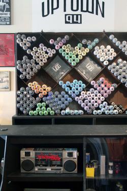 A display in the store with shelves full of colored spray paint bottles and a boombox. A sign at the top reads UPTOWN 94.