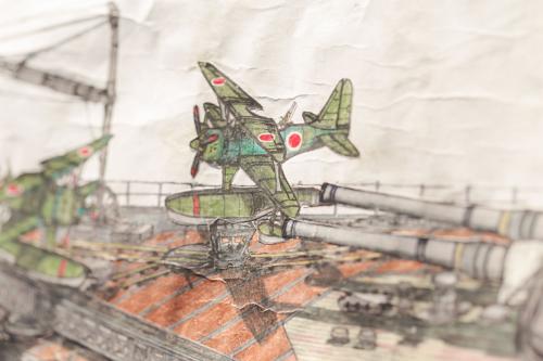 Closeup on a detailed color pencil drawing of a warship, showing green fighter planes on deck and gun turrets.