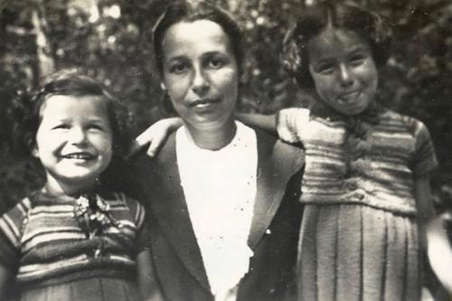 A woman and two young girls in matching striped tops pose and smile. Black-and-white family photo.