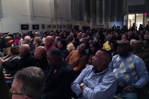A packed audience sitting shoulder to shoulder.