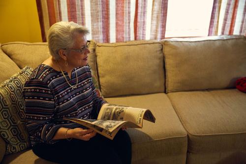 A woman on a couch at home holds open the magazine containing the previous spread, looking a bit dismayed to find a photo of herself.