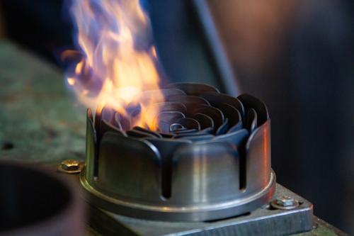 Close-up on a rose-shaped metal tool with blue and orange flames emanating from the petals.