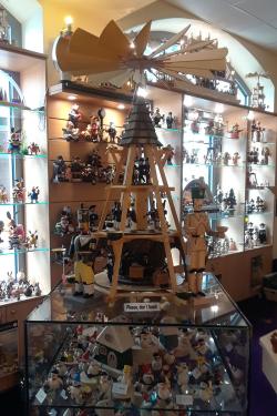 Display in a toy shop, with a wooden pyramid with three tiers, each with its own village scene. At the top is a propeller facing the ceiling.