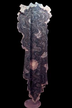 Dyed, printed textile dark blue and white hanging upright against a black background.