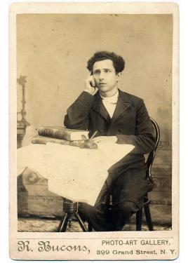Black-and-white portrait of a man seated at a small table, looking concerned. Below the image is a printed label: R. Bucons, Photo-Art Gallery, 399 Grant Street, N.Y.