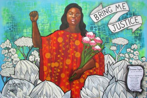 Mural of a Black woman in red dress, raising one fist and holding a bouquet of pink flowers. Words in a white ribbon design read BRING ME JUSTICE. A scroll design reads: In Memoriam Breonna Taylor.