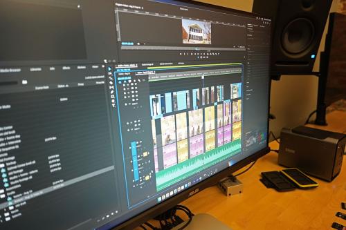 Close-up of the computer screen, showing several video clips and an audio track on a timeline.