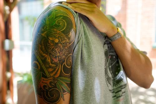 Close-up of a colorful tiger tattoo on a Black person’s upper arm. 