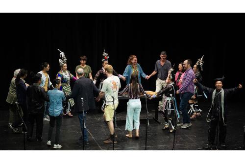 Performers and audience members join in a circle dance on stage.