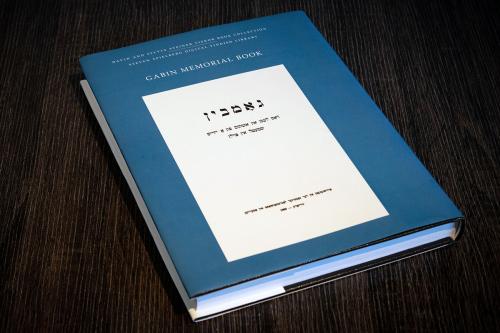 Closeup of a book with a blue cover titled GABIN MEMORIAL BOOK, plus the title in Hebrew. The book is bound to read from right to left.