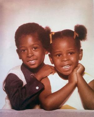Old studio portrait of young brother and sister, dressed up and smiling.