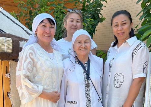 Four women in white tops pose smiling.
