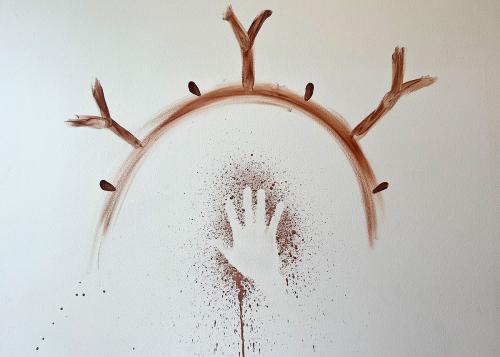 The negative of a handprint on a white wall, with brown paint splattered around it. Above, a brown arch with Y-shapes and dots radiating from it, as if growing out from the earth.