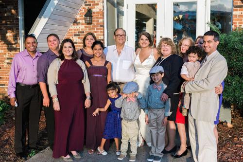 Family of eleven aadults and four small children pose together in formal wear.