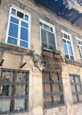 The exterior of a stone house with wrought-iron window screens.