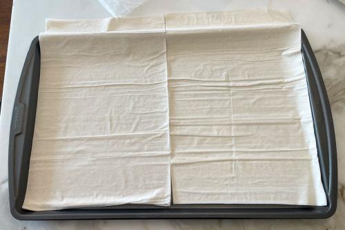 Thin sheets of phyllo dough laid on a metal baking tray.
