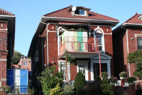 Exterior of two-story brick building, with a temporary structure built from the second story, like an enclosed balcony with walls of multicolored corrugated metal.