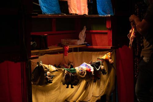 Backstage at the puppet show: several puppets lay draped over a curtain below the stage.