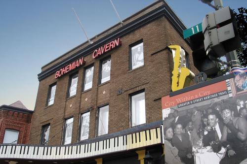 Exterior of a three-story brick building with name in red, Bohemian Cavern, and a design of black and white piano keys around the first-story awning.