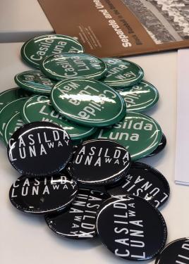 Close-up of green and black campaign buttons reading “Casilda Luna Way”