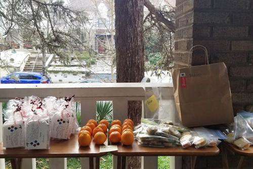 Closeup on a table neatly lined with cellophane baggies, mandarins, and other bags full of cookies and treats. 