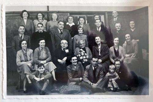Black-and-white photographer with rough edges, showing 26 people posing in four rows, including three small children.
