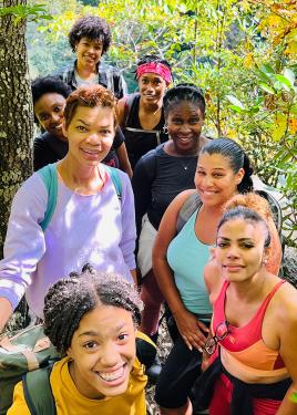 Eight people pose and smile along a hiking trails.