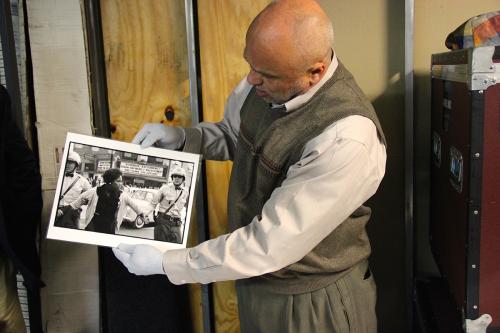 Museum founder David Pilgrim holds up a black-and-white photo of a Black woman held by two white police officers.