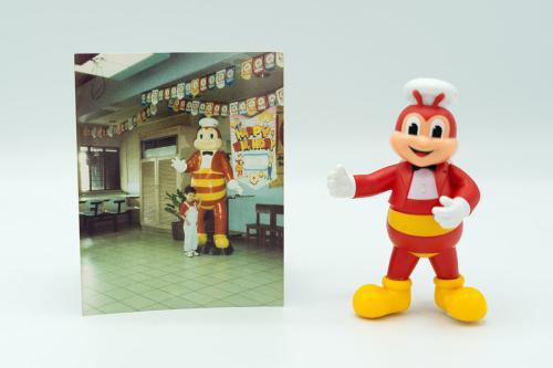 On the left, photo of a young boy in a restaurant, posing next to a statue of a large humanoid bee with red coat jacket and red and yellow striped abdomen. On the right, smaller figurine of the same bee.