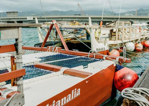 Two docked double-hull canoes, both painted red and white.