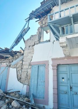 A two-story building with blue doors and balcony, destroyed.